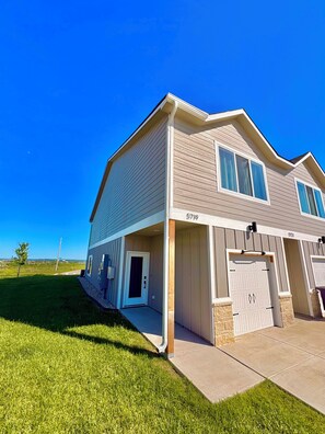 Ein zweistöckiges Haus mit Garage und überdachter Veranda, strahlend blauer Himmel.