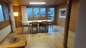 A wooden-paneled room with a dining table and chairs, a lamp, and a framed picture on the wall.