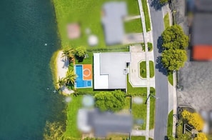 Vue aérienne d’une propriété comprenant un terrain de basket-ball, une piscine et un grand bâtiment doté d’un toit plat.