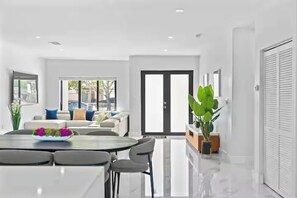 Un interior moderno con comedor, un conjunto de sofás y un ventanal amplio.