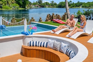 Un espace aménagé au bord de la piscine, avec des chaises longues, une piscine et une vue sur un lac.
