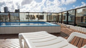 Ein Pool auf dem Dach mit Liegestühlen, einer Whirlwanne und Blick auf die Stadt.