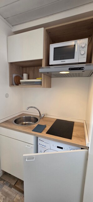 A compact kitchen with a built-in microwave, a stainless steel sink, and a dishwasher. - Apartment 'Ocean Blue' with Unmatched Sea View, Private Parking and Air Conditioning (Sant'Andrea di Rovereto)