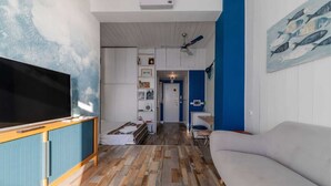A compact living space with a television, a sofa, a dining area, and a kitchen. - "Ocean Blue" – A Gem with Unmatched Sea View, Wi-Fi & Air Conditioning (Sant'Andrea di Rovereto)