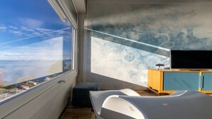 A modern room with a large window, a flat-screen TV, and a wooden cabinet. - "Ocean Blue" – A Gem with Unmatched Sea View, Wi-Fi & Air Conditioning (Sant'Andrea di Rovereto)