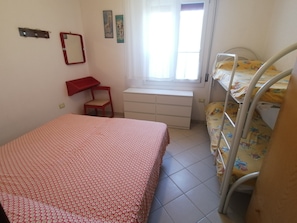Un dormitorio con literas, un escritorio, una silla y una ventana.