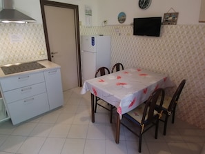 Una cocina pequeña con estufa, refrigerador y mesa de comedor con sillas.