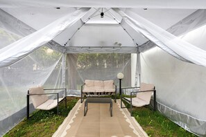 A tent with a cushioned bench and chairs, a table, and a lamp. - Apartment 'Le Margotte - Rome' with Private Garden, Wi-Fi and Air Conditioning (Stiava)