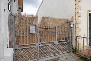 A gated entrance with a bamboo fence, a metal gate, and a sign with numbers. - Apartment 'Le Margotte - Rome' with Private Garden, Wi-Fi and Air Conditioning (Stiava)