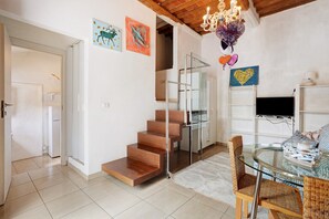 A modern interior with a staircase, a glass table, wicker chairs, and artwork on the walls. - Holiday Home 'Le Margotte - Apartment Lola' with Garden, Wi-Fi and Air Conditioning (Stiava)