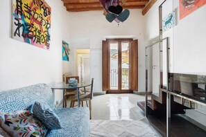 A living room with a sofa, a glass table, and a TV. There is a door leading to an outdoor area. - Holiday Home 'Le Margotte - Apartment Lola' with Garden, Wi-Fi and Air Conditioning (Stiava)