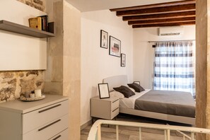 Ein Schlafzimmer mit Bett, Nachttisch, Wandregal und einem Babybett.