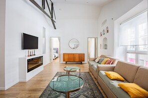 Ein modernes Wohnzimmer mit einer Couch, einem Glastisch, einem Fernseher und einem Kamin.