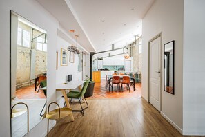 Eine moderne Küche mit weißen Schränken, ein Essbereich mit Holzsesseln und ein großes Fenster.