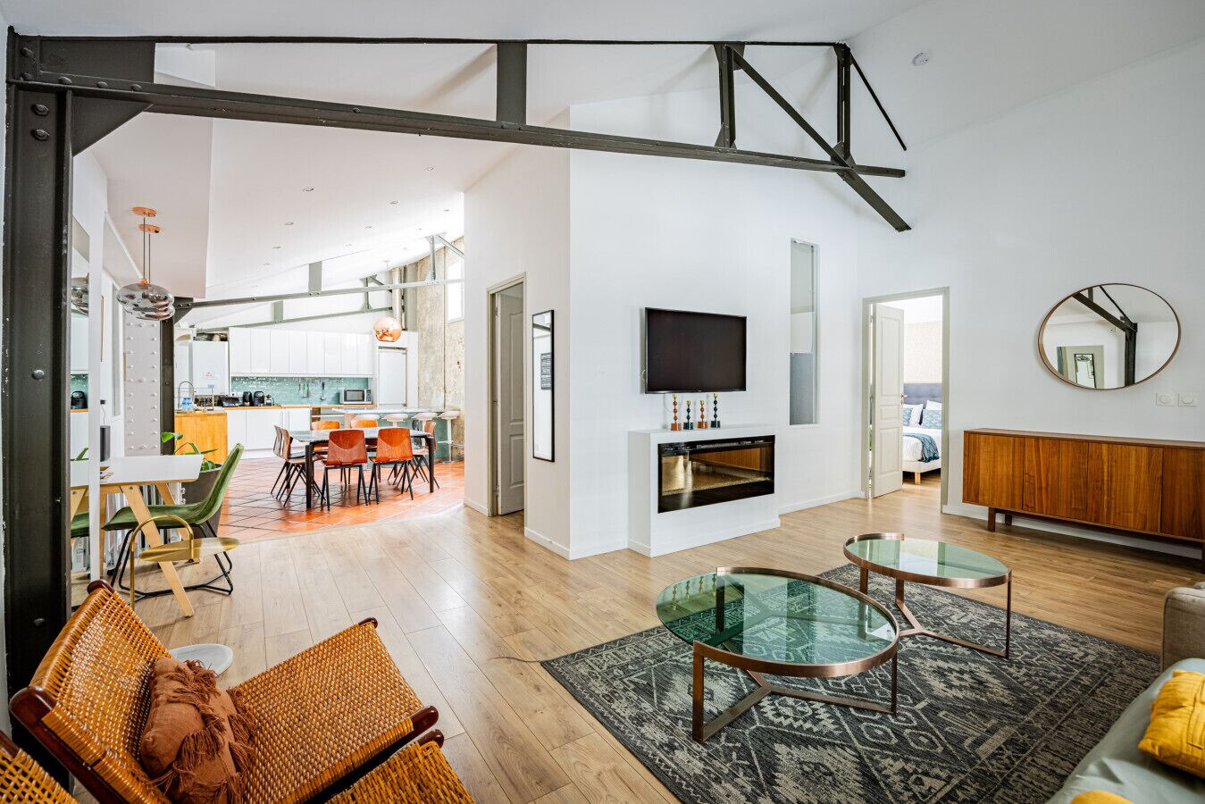 An open-plan living area with a dining space, kitchen, and a TV mounted on the wall.