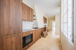 Eine moderne Küche mit Holzschränken, einem schwarzen Backofen und einer weißen Arbeitsplatte.