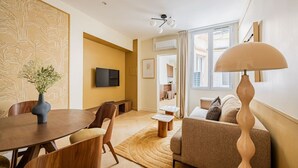 Ett modernt vardagsrum med en matplats, en soffa, en tv och en lampa.