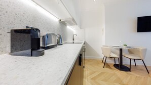 Una cucina moderna con un piano di lavoro in marmo, una macchina da caffè, un tostapane e un bollitore. C'è un'area pranzo con tavolo e sedie.