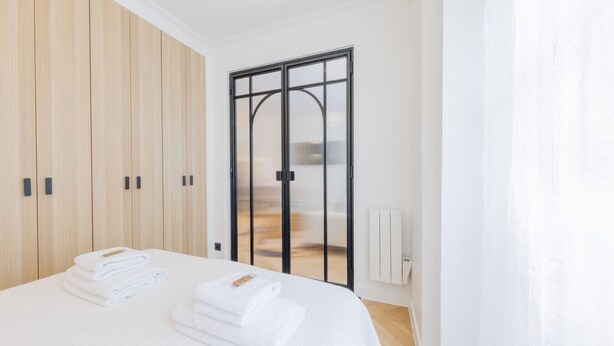 Una camera da letto con un letto, un armadio in legno, una porta scorrevole in vetro e un termosifone.