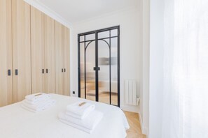 Une chambre à coucher comprenant un lit, une armoire en bois, une porte-fenêtre coulissante et un radiateur.