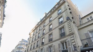 Un edificio a più piani con uno stile architettonico classico, dotato di balconi e persiane.