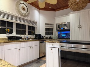 A modern kitchen with white cabinetry, a built-in oven, a microwave, and a coffee maker. - Quiet Spacious 5-bedroom house in lovely North Palmetto Point with AC (North Palmetto Point)