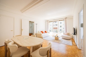 A modern living room with a dining area, a sofa set, and a television. - Premium 1-Bedroom - Trocadéro - Eiffel Tower - Paris 16 (Paris)