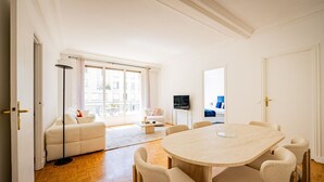 Ein geräumiger Wohnbereich mit rundem Tisch, einer Couch und einem Fernseher.