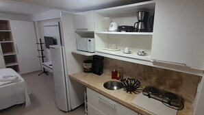 Una cucina compatta con forno a microonde, macchina del caffè e lavandino.