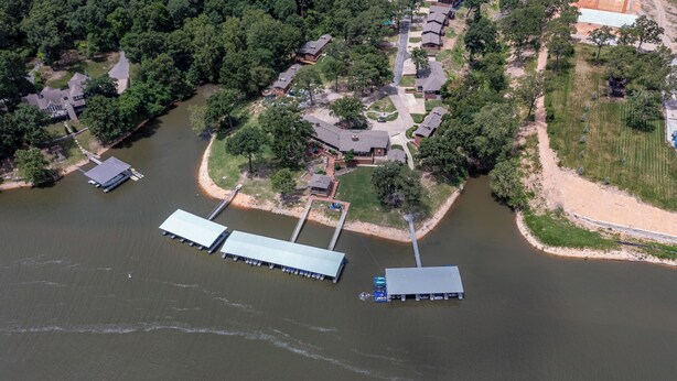 An aerial view of a lakeside property with several docked boats, a bridge, and a mix of residential and commercial buildings.