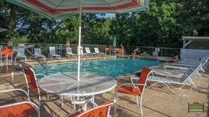 A pool area with lounge chairs, a table, and umbrellas.