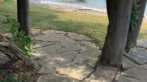 Un chemin de pierres qui mène à une jetée, où se trouvent des chaises, et d’où l’on a une vue sur l’eau.