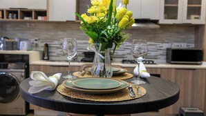 A dining table with a vase of flowers, plates, and wine glasses set for a meal. - Atelier Luxe Home, Charming Modern Styled 1bedroom in Kileleshwa (Nairobi)