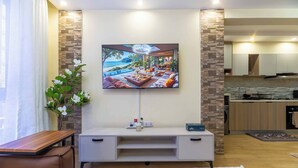 A modern living room with a flat-screen TV, a sofa, a coffee table, and a dining area. - Atelier Luxe Home, Charming Modern Styled 1bedroom in Kileleshwa (Nairobi)