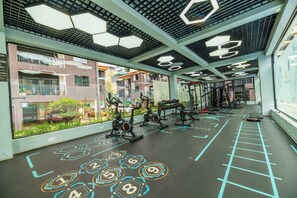A gym with exercise equipment, a hexagonal floor pattern, and large windows overlooking a residential area. - Atelier Luxe Home, Charming Modern Styled 1bedroom in Kileleshwa (Nairobi)