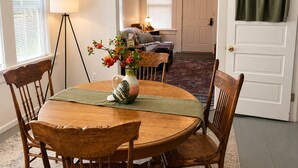 A dining area with a round wooden table, chairs, a vase with flowers, and a lamp. - Mt. Shasta Basecamp. Walkable downtown. Near Waterfalls, Castle Crags & Fishing. (Dunsmuir)