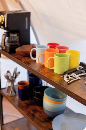 A wooden shelf with colorful mugs, a coffee maker, and keys.