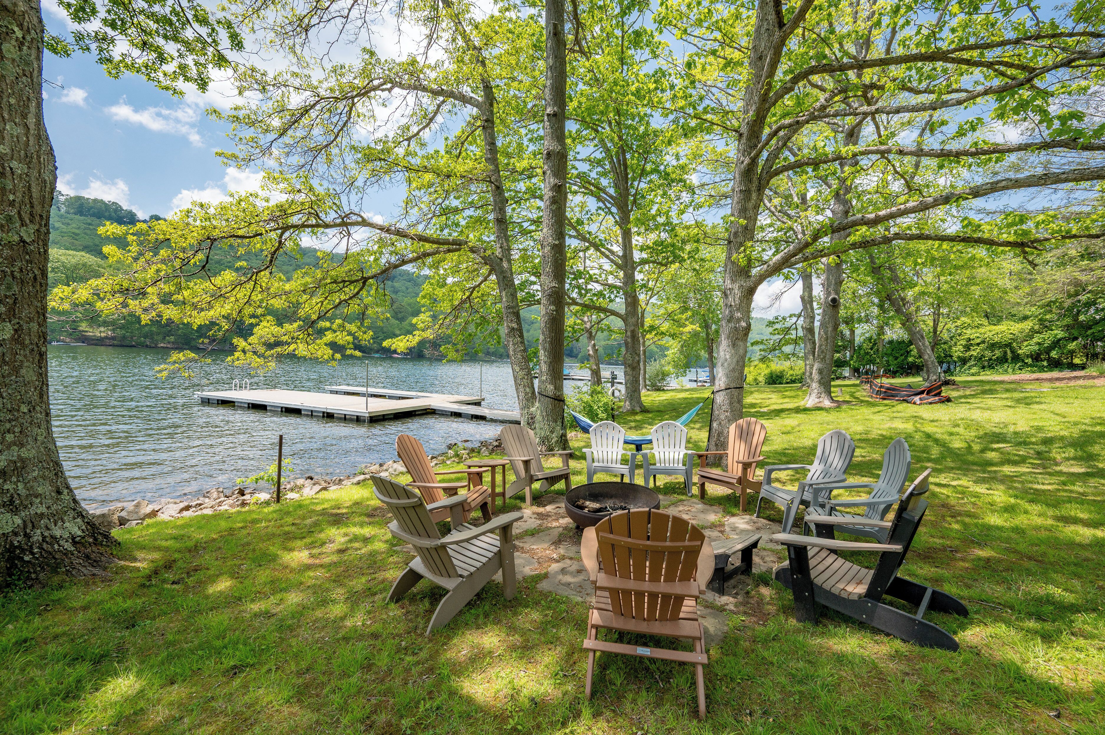 Zona de estar al aire libre frente al lago, con sillas Adirondack y una chimenea.