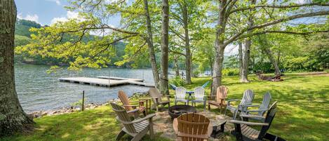 Zona de estar al aire libre frente al lago, con sillas Adirondack y una chimenea.