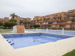 Una piscina amb una tanca blanca, envoltada per edificis d'apartaments.