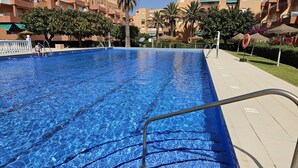 A swimming pool with clear blue water, surrounded by a tiled deck and palm trees. - Apartment 'Duplex Jardines Del Mar' with Sea View, Wi-Fi and Air Conditioning (Salobreña)