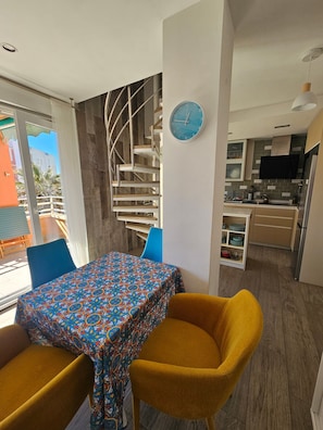 Une cuisine moderne dotée d’un four encastré, un coin repas avec une nappe à motifs et un escalier au design original.