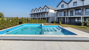 Ein modernes Hotel mit Schwimmbad, mehreren Balkonen und einem gepflegten Garten.