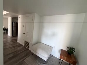 A modern room with a white sofa, a wooden side table with a plant, and a door leading to another room. - Cozy Top Floor 3 BR Apartment - Small Groups Haven (Austin)