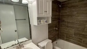Un baño con lavamanos blanco, espejo, inodoro y bañera.