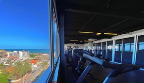 A gym with exercise equipment and a view of a coastal cityscape. - Villi Desing - Miramar Hospedagens  (João Pessoa)