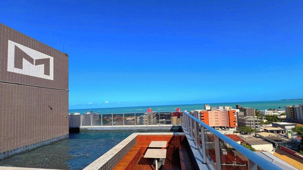 Une piscine sur le toit offrant une vue sur l’océan et le paysage urbain.