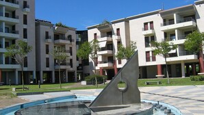 A modern apartment building with balconies, a central courtyard, and a pool area. - Apartment Overlooking the sea and the Marina (Lignano Sabbiadoro)