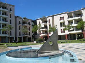 Ein modernes Apartmenthaus mit Balkonen, einem Innenhof und einem Poolbereich.