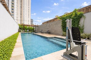 Ein Pool mit Liegestühlen, einer Wasserrutsche und Blick auf hohe Gebäude.